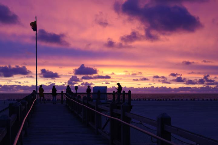 Der Himmel verwandelt sich zum nordwestlich gelegenen Strandübergang am Norddorfer Badestrand in ein Gemälde aus leuchtenden Farben, wenn die Sonne langsam im Meer versinkt – ein Anblick der einfach atemberaubend ist