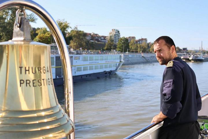 Der Kapitän Krisztián Mészáros navigiert am Außensteuerstand gekonnt seinen Flusskreuzer Richtung Anlegestelle, an der bereits ein anderes Schiff festgemacht hat, um im Päckchen anzulegen
